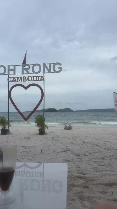 Part of a Koh Rong Cambodia heart sign beside a grey beach and sea beneath storm clouds.